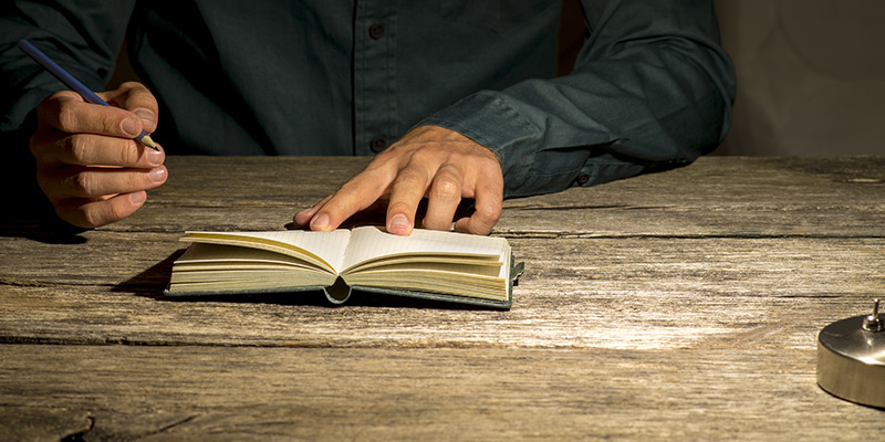 Author schreibt in sein Buch und hält dabei einen Füller in der rechten Hand